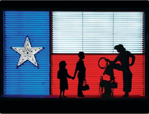 Shadows of children and a cowboy in front of the Texas Neon Flag