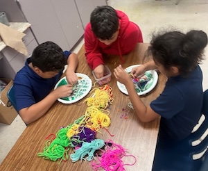 Mark Twain students use paper plates as makeshift looms and weave artworks for the "Explore the Lone Star: Field to Fabric" Texkit.