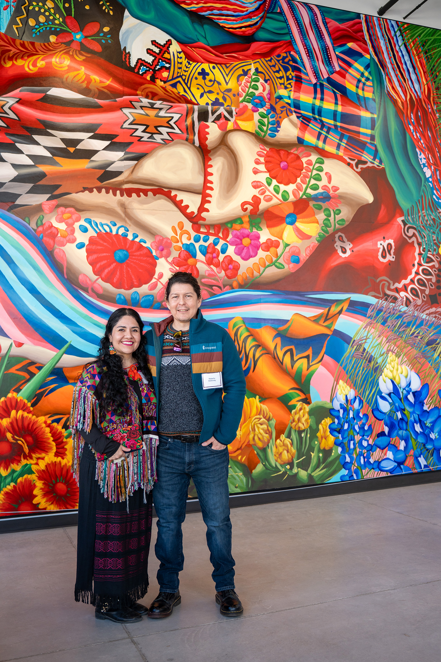 Artist couple Sandra Gonzalez McKinney and Malachy McKinney stand in front of &ldquo;Texas Tapestry