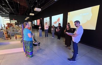 Docent Ellen Brooker welcomes Community Translations students at her station on the ITC exhibit floor. Brooker, a Chickasaw, often incorporates American Indian stories and language in her presentations.