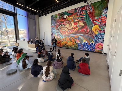 Young students in the lobby of the ITC listening to Liz speak about the mural.