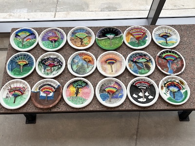 Student activity results from the "Explore the Lone Star: Field to Fabric," a lesson on Texas textiles. 18 paper plates with paint and textile pieces