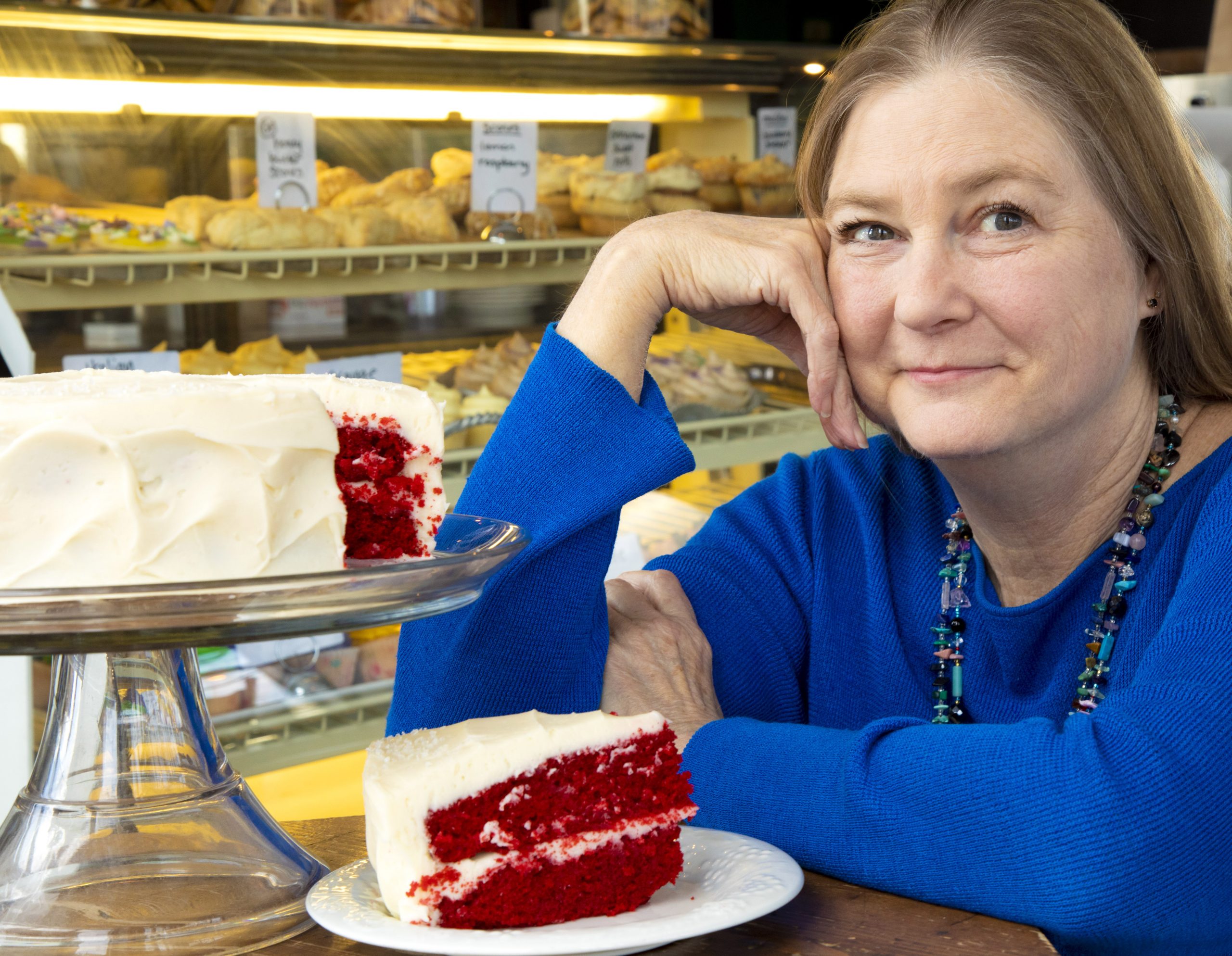 Rebecca Sharpless sitting next to a slice of red velvet cake